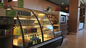 Un bar de aperitivos con un expositor de vidrio que contiene diversas bebidas y tentempiés.