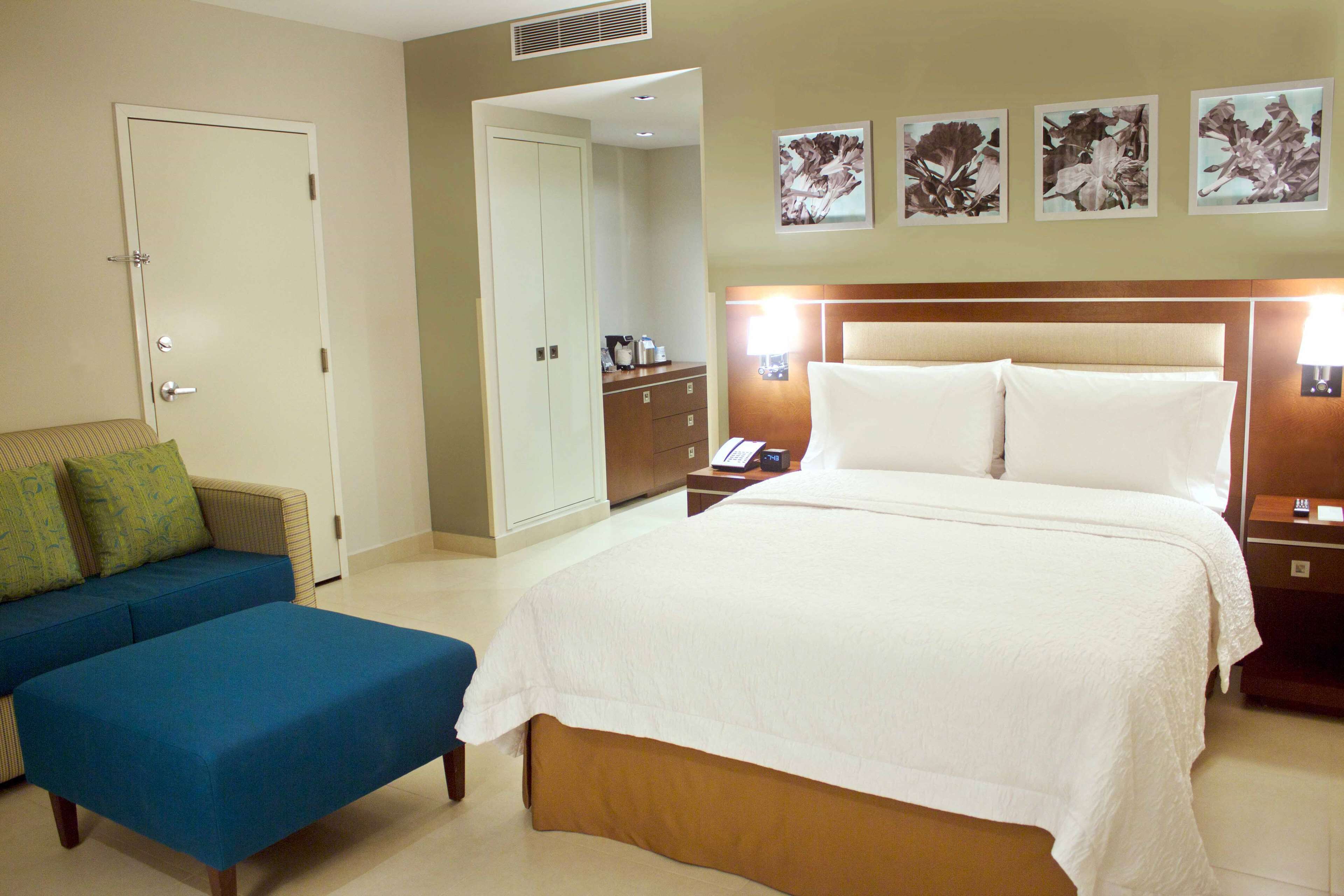 Quarto de hotel com cama, sofá, escrivaninha e guarda-roupa.