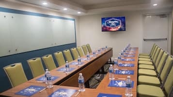 Un salón de conferencias con una larga mesa, sillas, botellas de agua y tarjetas de identificación.