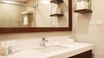 Un baño de hotel con un lavamanos blanco, un espejo y estantes de madera encima.