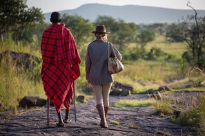 Two people walking on a rocky path in a natural setting. - Elewana Serengeti Pioneer Camp (Bariadi)