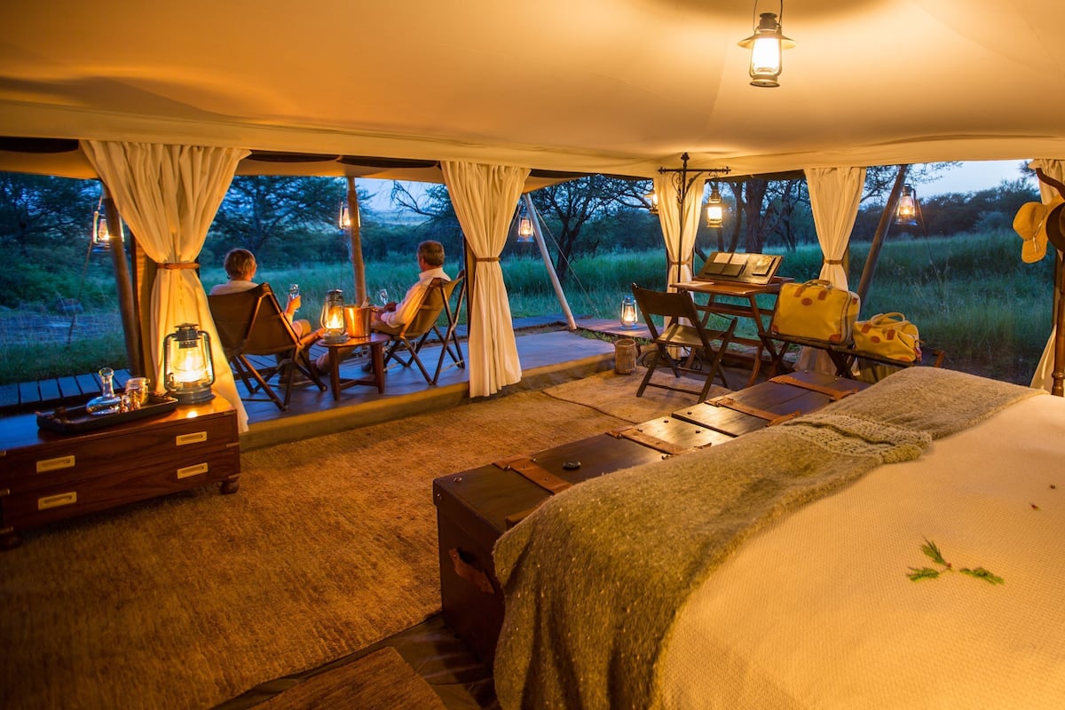Una tenda arredata con un letto, un tavolo, sedie e vista sull'esterno.