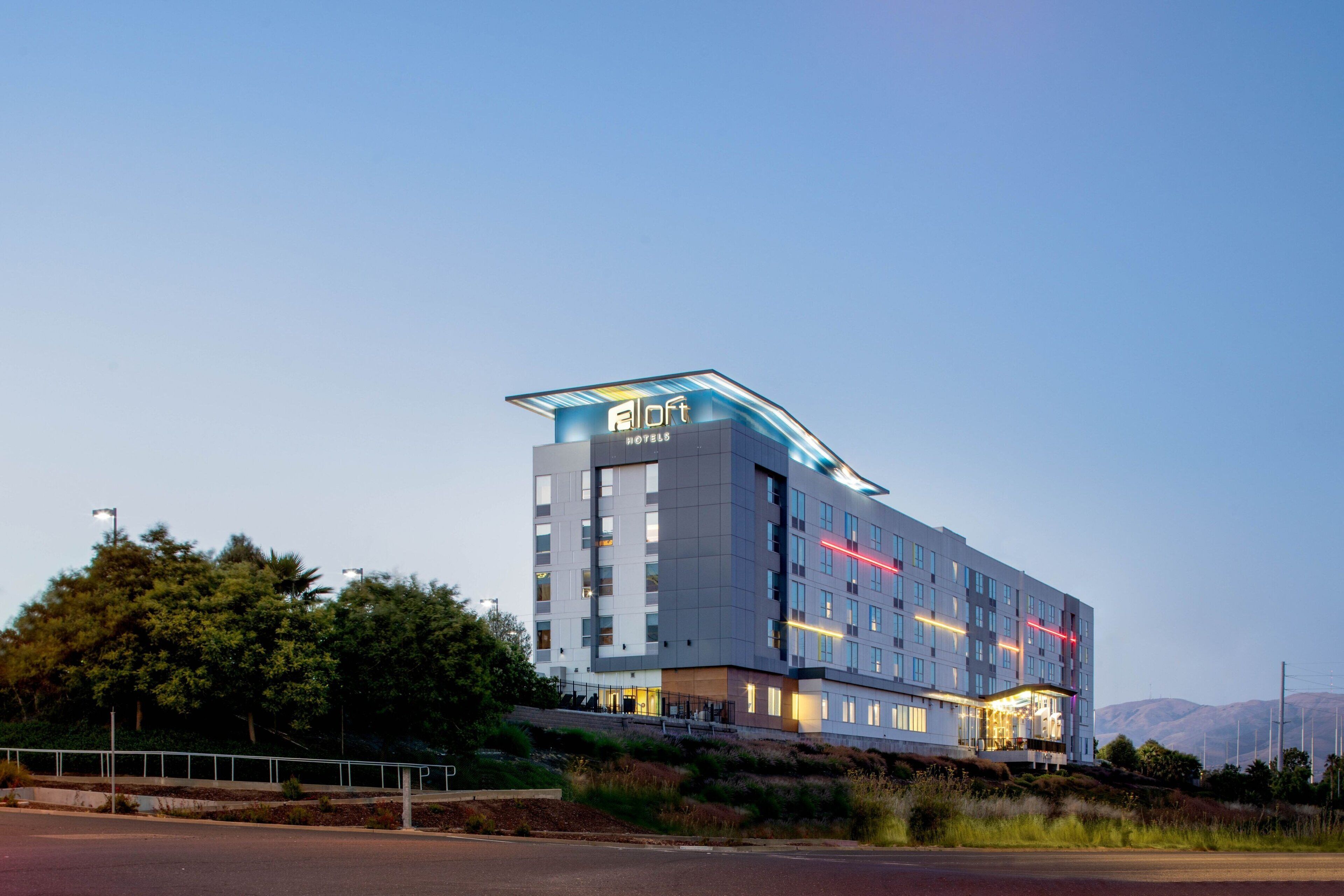 A modern hotel with a flat roof, multiple floors, and a prominent sign.