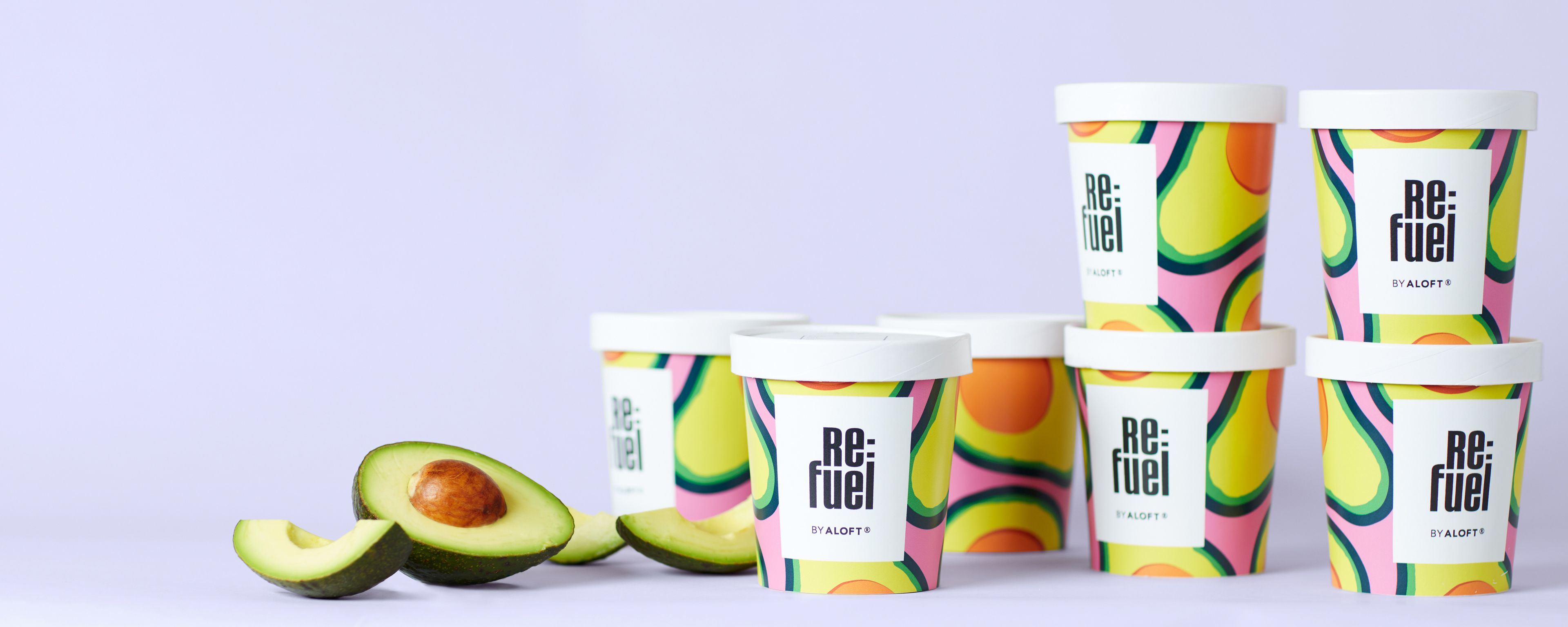 Seis envases de Re:Fuel de ALOFT® con diseños coloridos, y dos mitades de aguacate.