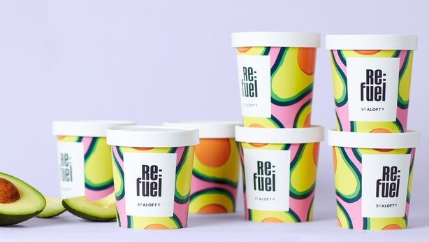 Six containers of Re:Fuel by ALOFT® with colorful patterns, and two halves of an avocado. - Aloft by Marriott Santa Clara (San Jose)