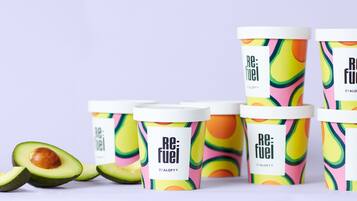 Seis envases de Re:Fuel de ALOFT® con diseños coloridos, y dos mitades de aguacate.