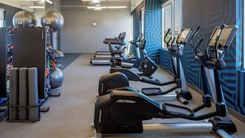 A gym with treadmills, elliptical machines, and exercise balls.