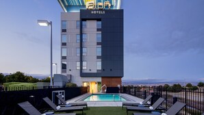 Um hotel moderno com piscina no terraço, espreguiçadeiras e vista para a paisagem.