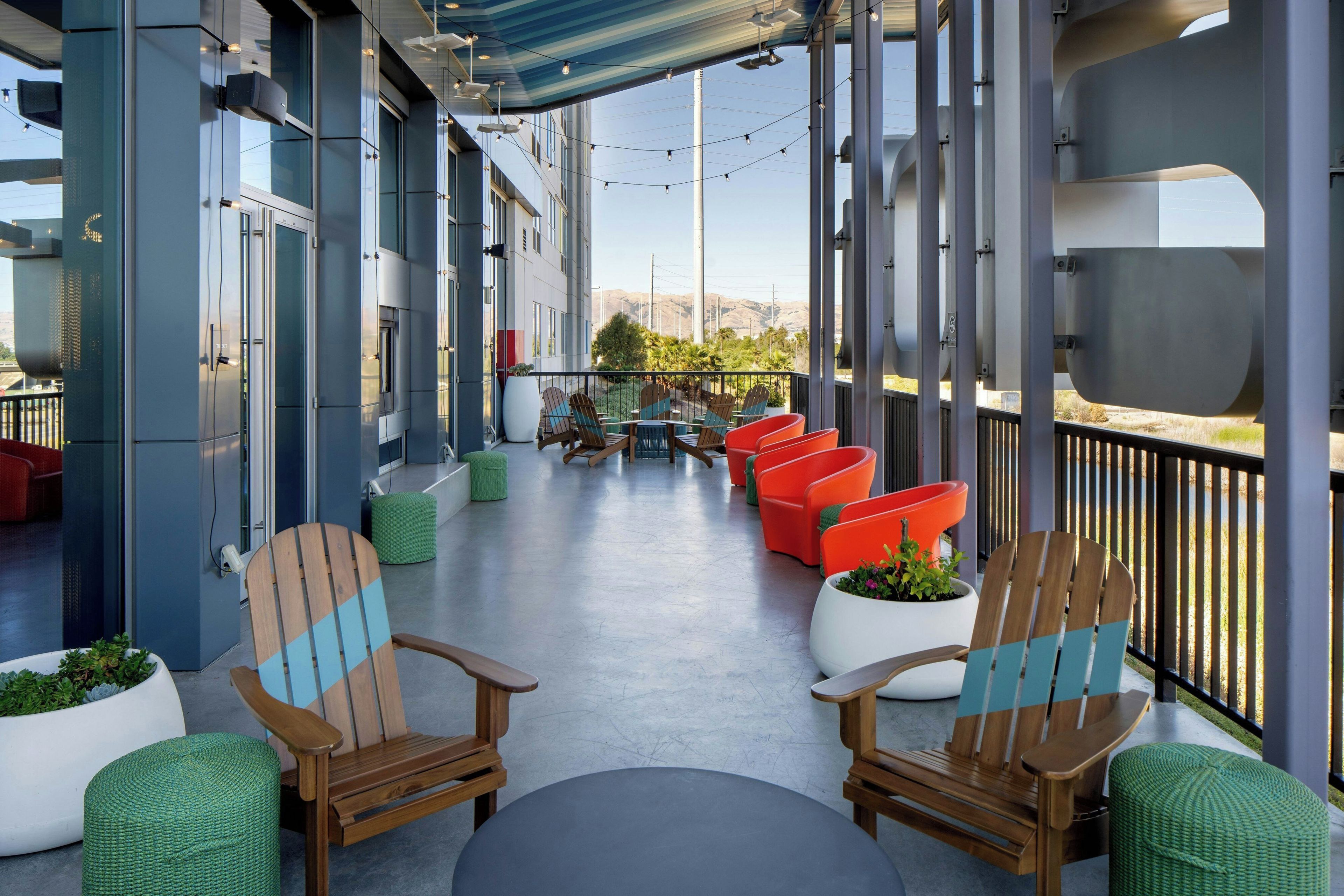 A covered outdoor seating area with chairs and tables, overlooking a mountainous landscape.