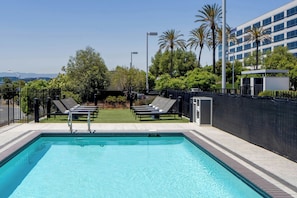 A rectangular swimming pool with two lounge chairs and a metal fence. - Aloft by Marriott Santa Clara (San Jose)