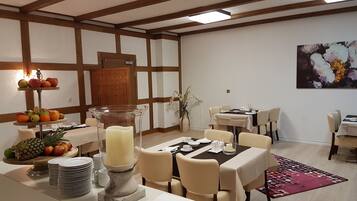 Comedor con mesas de buffet, frutas y un centro de mesa con velas.