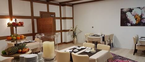 Comedor con mesas de buffet, frutas y un centro de mesa con velas.