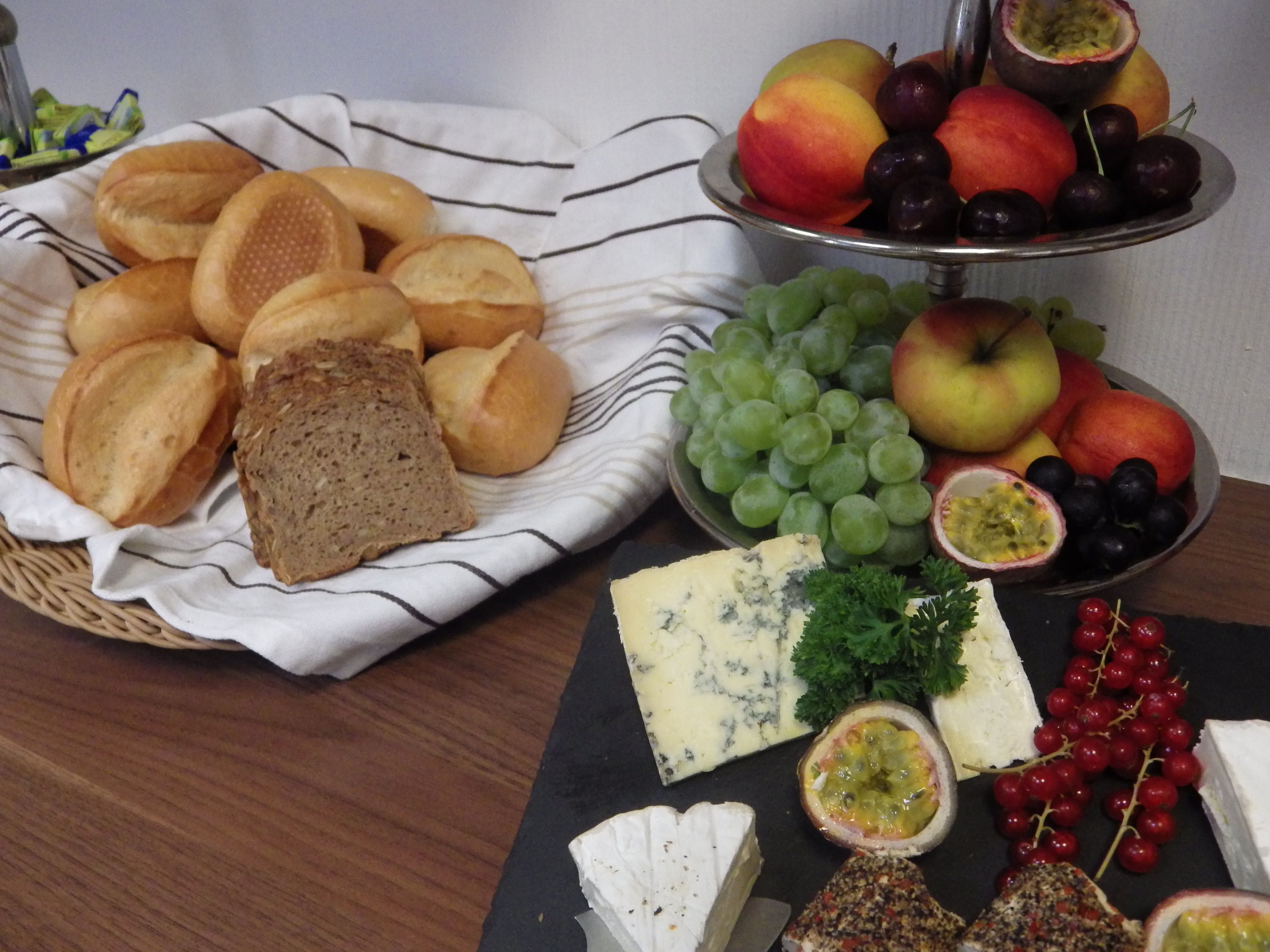 Una mesa con diversos alimentos, como pan, queso, uvas y frutas.