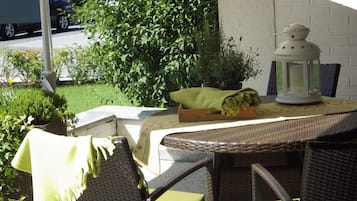 An outdoor patio with wicker furniture, a table with a lantern, and potted plants.