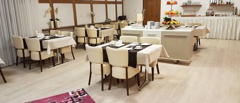 A dining area with multiple tables and chairs, a buffet station, and a patterned rug on the floor.