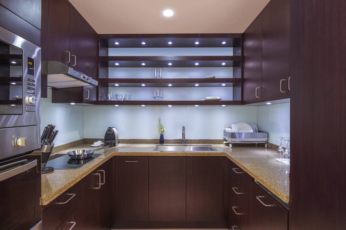 Una cocina moderna con armarios de madera oscura, electrodomésticos de acero inoxidable y encimera de granito.