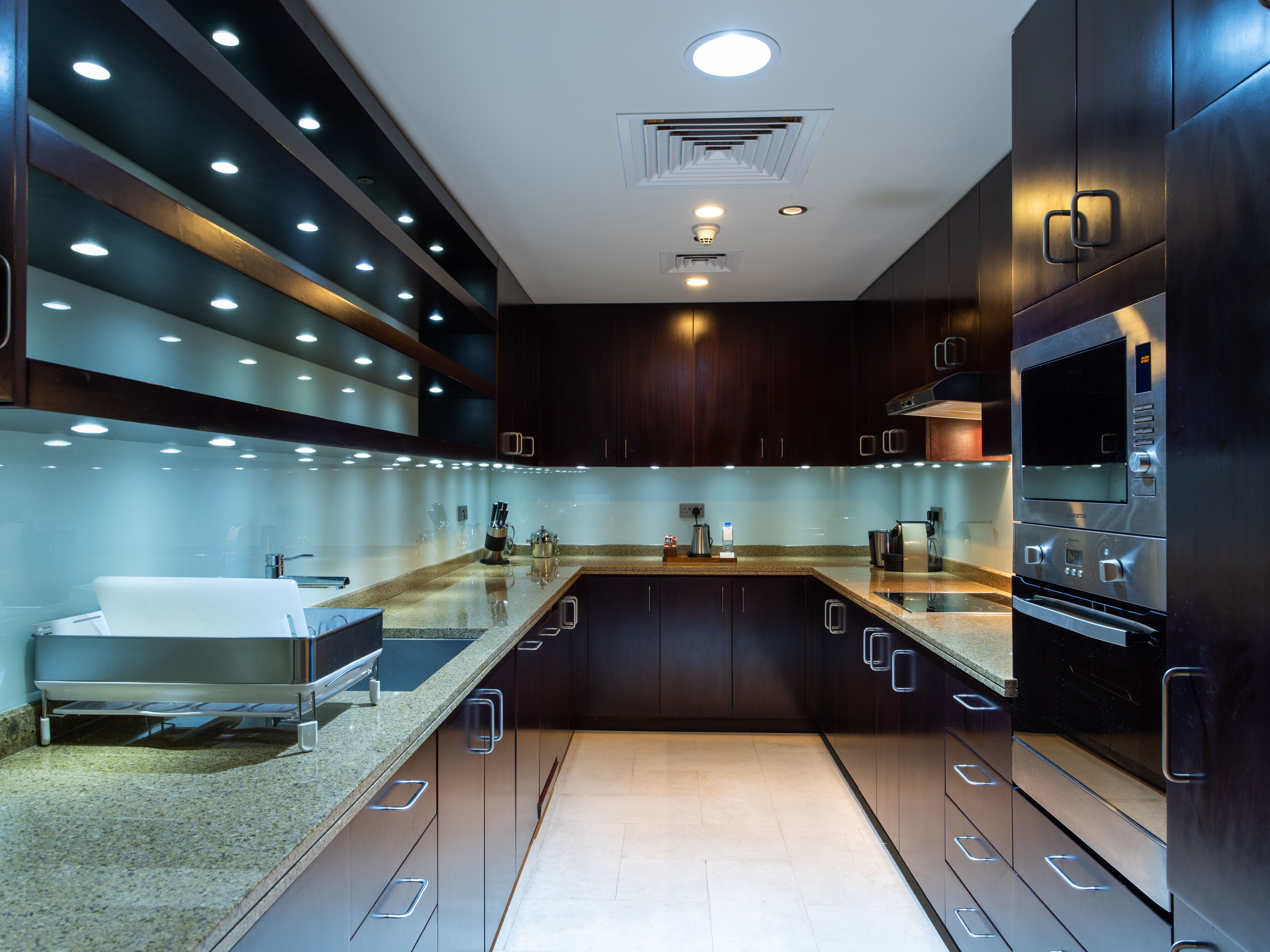 Une cuisine moderne avec des meubles de couleur sombre, des appareils électroménagers en acier inoxydable et un plan de travail en granit.