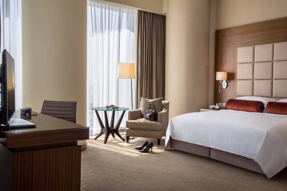 Una habitación de hotel con una cama, un escritorio, una silla, una mesa y un televisor.