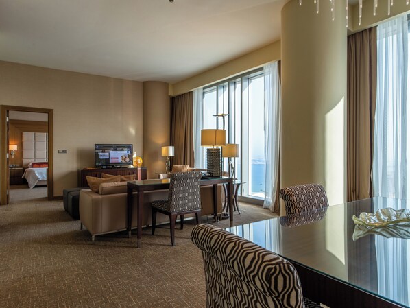Une chambre d’hôtel avec un lit, une télévision, un bureau avec une lampe, une chaise et une vue sur l’océan.