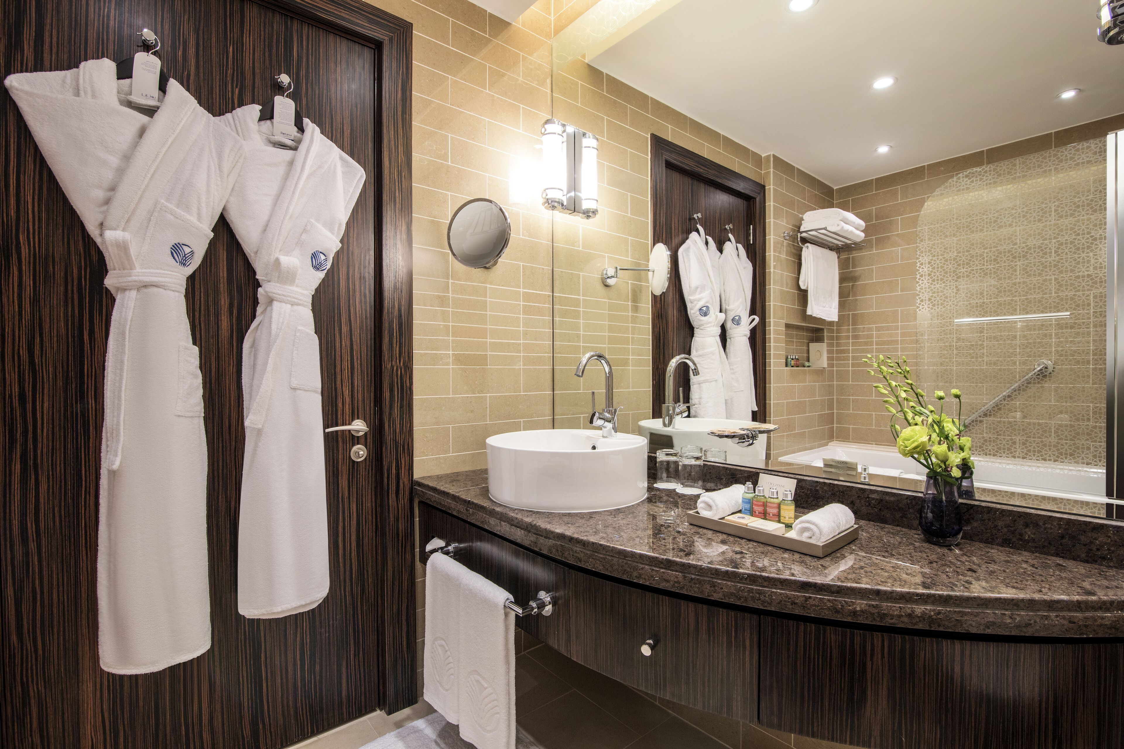 A modern bathroom with a large mirror, a sink, and a shower area.