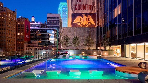An outdoor pool area with modern seating and a view of city buildings. - Hilton Garden Inn Downtown Dallas (Dallas)