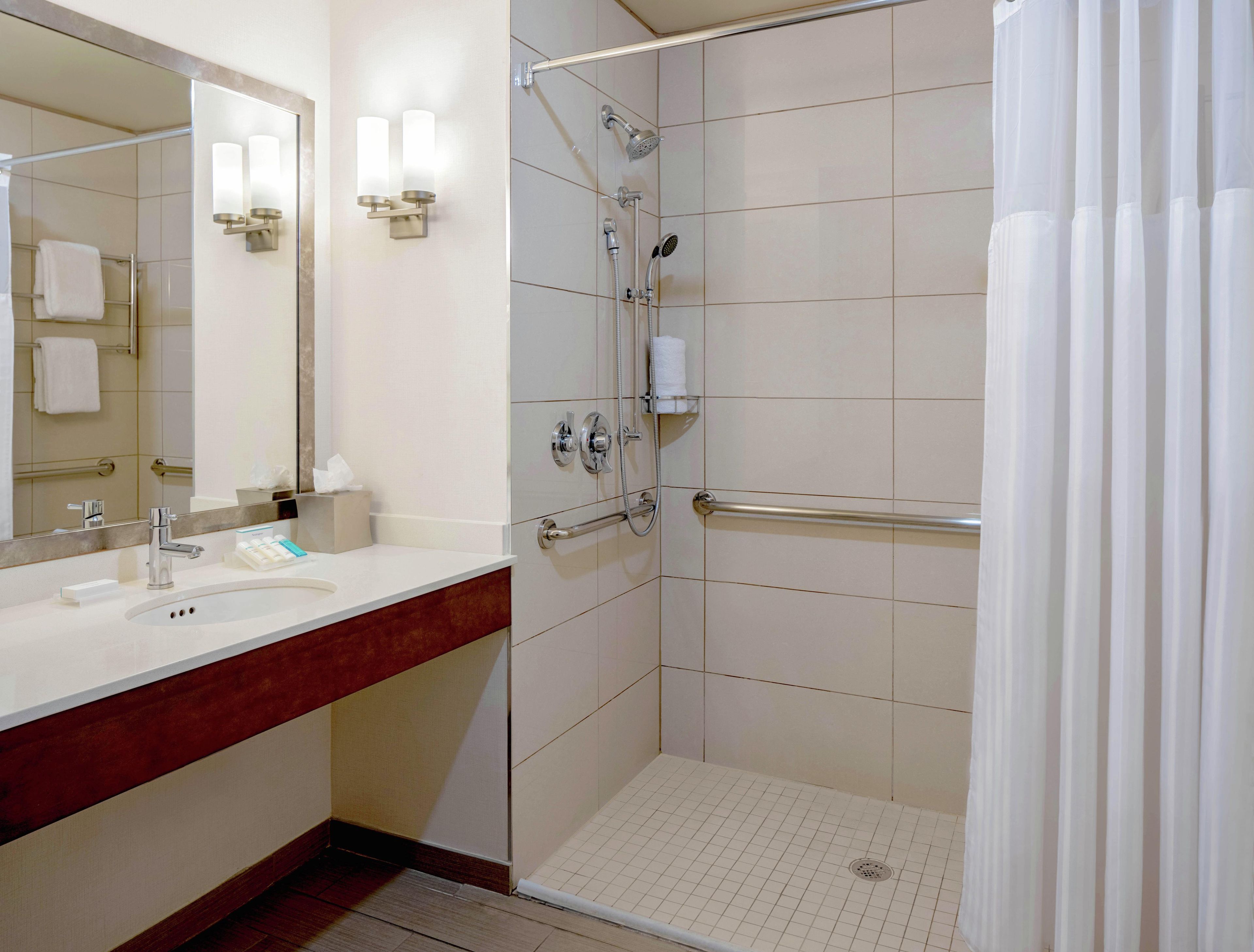 Een moderne badkamer met een douche, wastafel en spiegel.