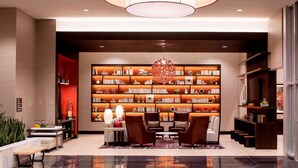 A modern lobby with a large bookshelf, comfortable seating, and a stylish chandelier. - Hilton Garden Inn Downtown Dallas (Dallas)