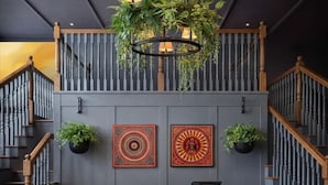 A reception desk with a hanging plant, two wall-mounted lamps, and two framed artworks. - Hilton Garden Inn Downtown Dallas (Dallas)