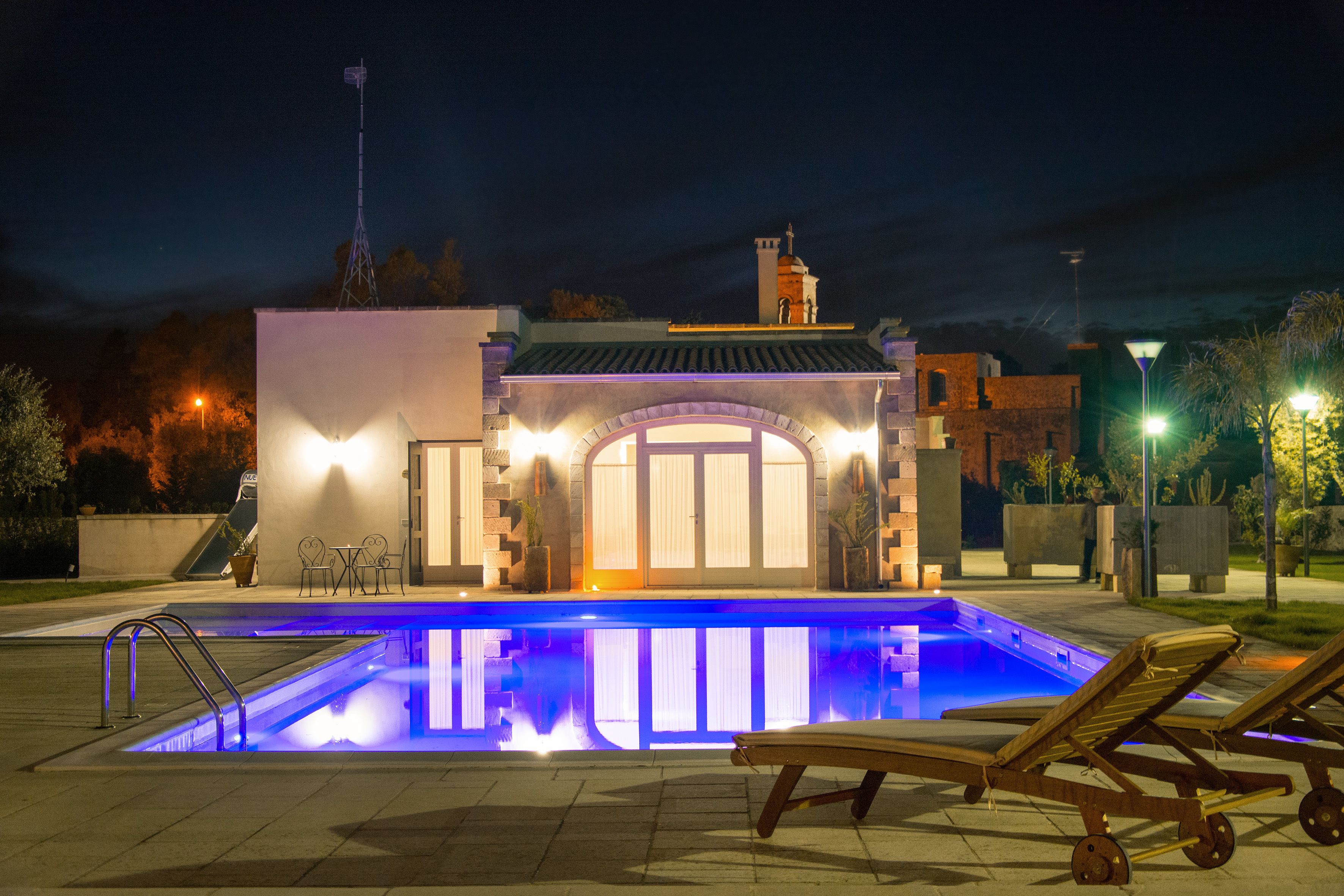 Una piscina con sillas de descanso y un pequeño edificio con techo de tejas.