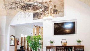 A dining area with a high arched ceiling, a large painting, and a wine rack. - Relais Tenuta Campì (Martano)