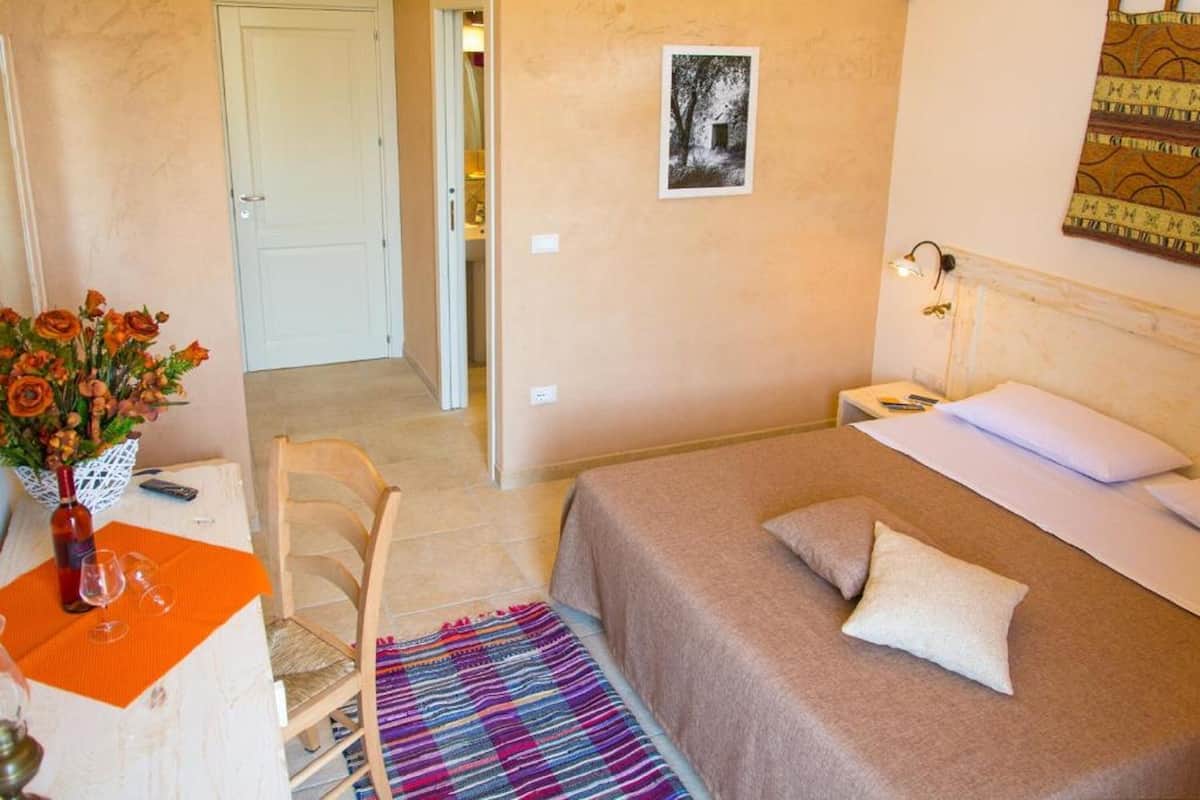 A bedroom with a bed, bedside table, lamp, and a wall-mounted picture.