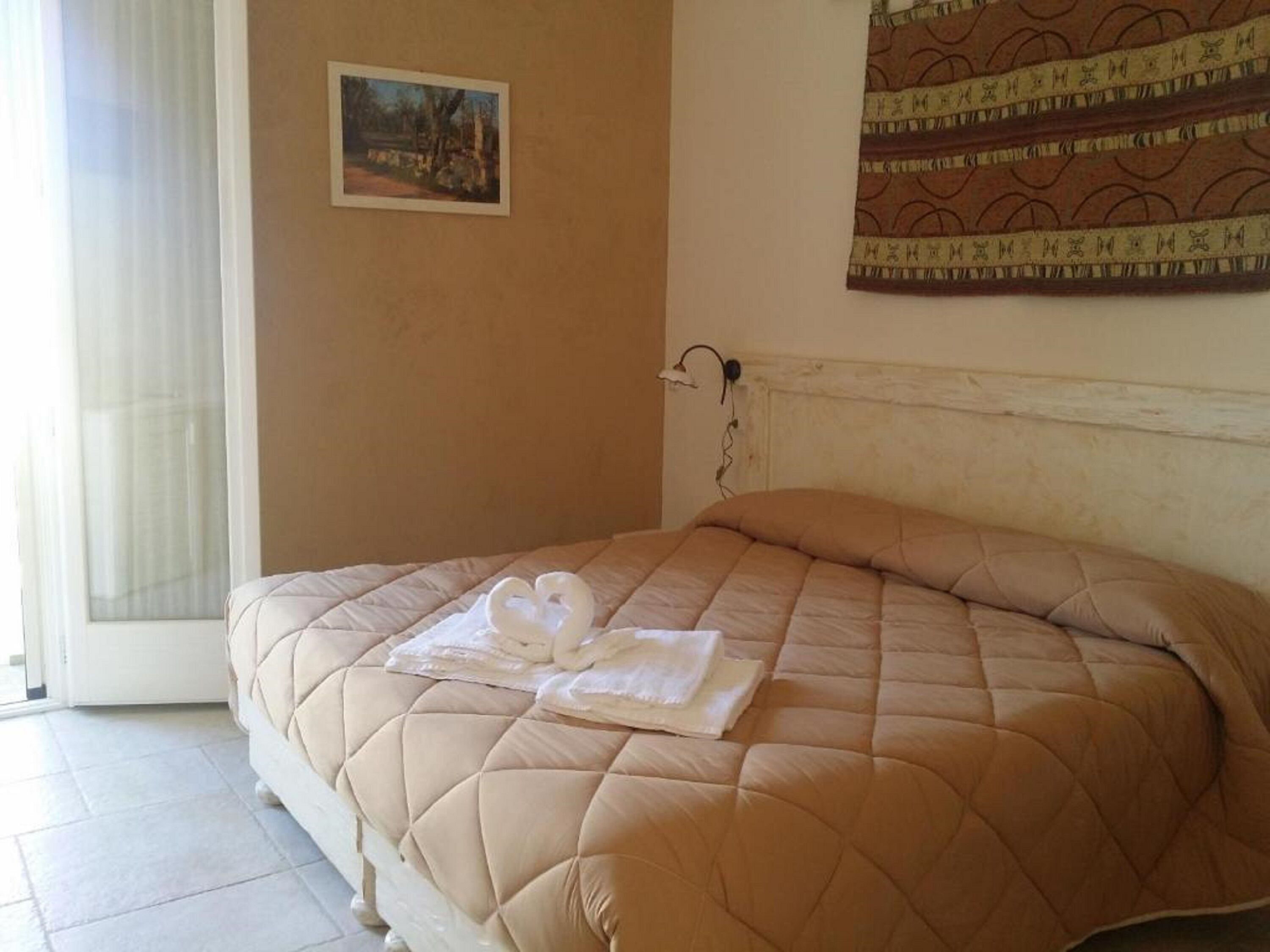 A neatly made bed with a quilted cover and a towel folded on top.