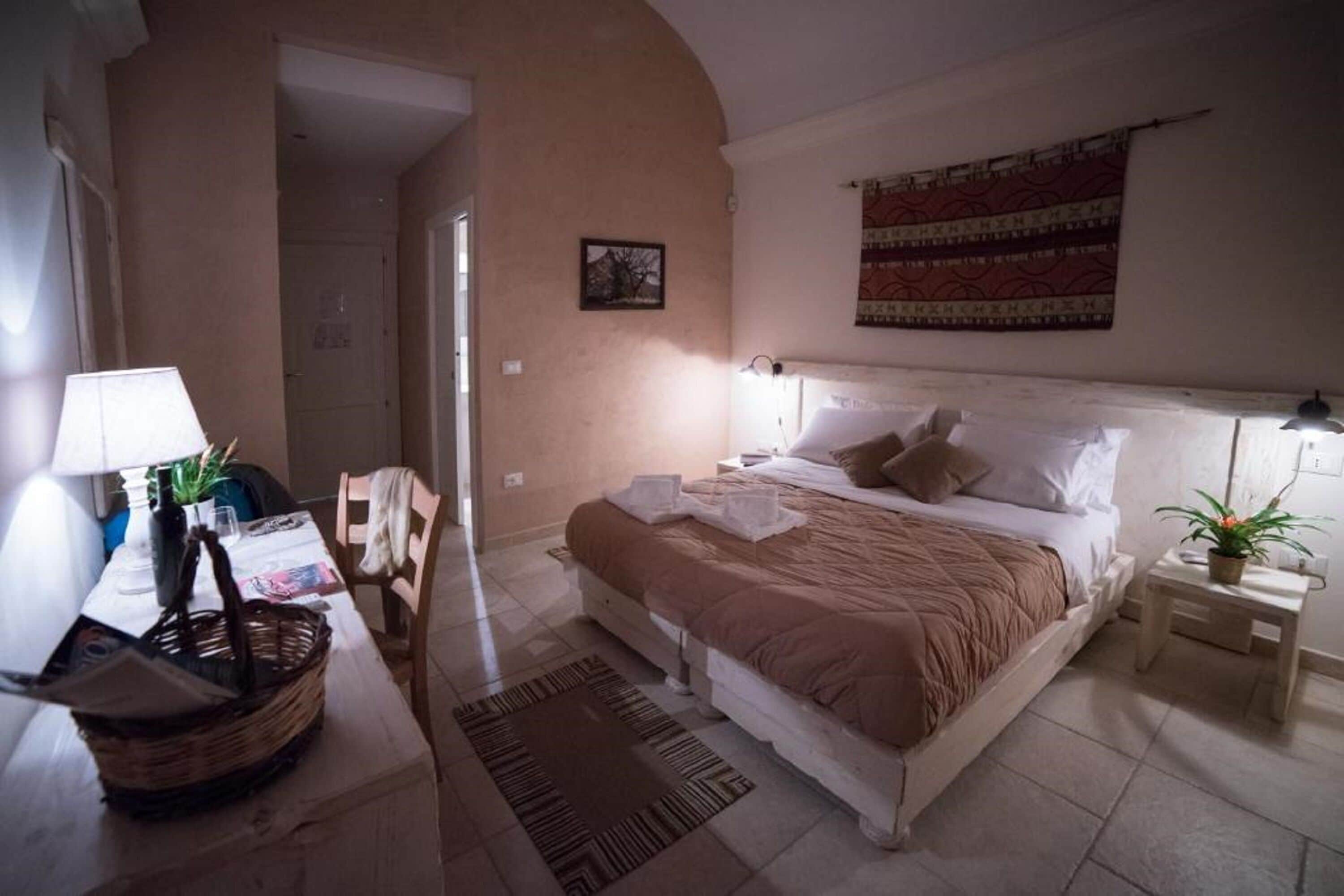 Ein Schlafzimmer mit Bett, Nachttischen, einer Lampe, einem Sessel und einer Wanddekoration.