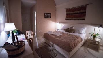 Ein Schlafzimmer mit Bett, Nachttischen, einer Lampe, einem Sessel und einer Wanddekoration.