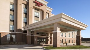 A hotel with a 'Welcome' sign, a covered entrance, and a clear blue sky. - Hampton Inn Lincoln Airport (Lincoln)