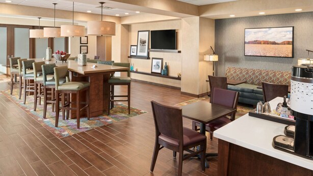 A hotel lobby with a bar area, seating, and a television mounted on the wall. - Hampton Inn Lincoln Airport (Lincoln)