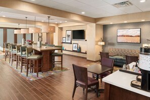 A hotel lobby with a bar area, seating, and a television mounted on the wall. - Hampton Inn Lincoln Airport (Lincoln)