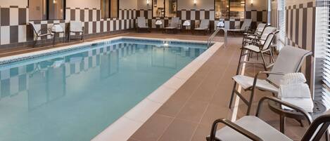 A hotel pool area with multiple lounge chairs and a long pool.