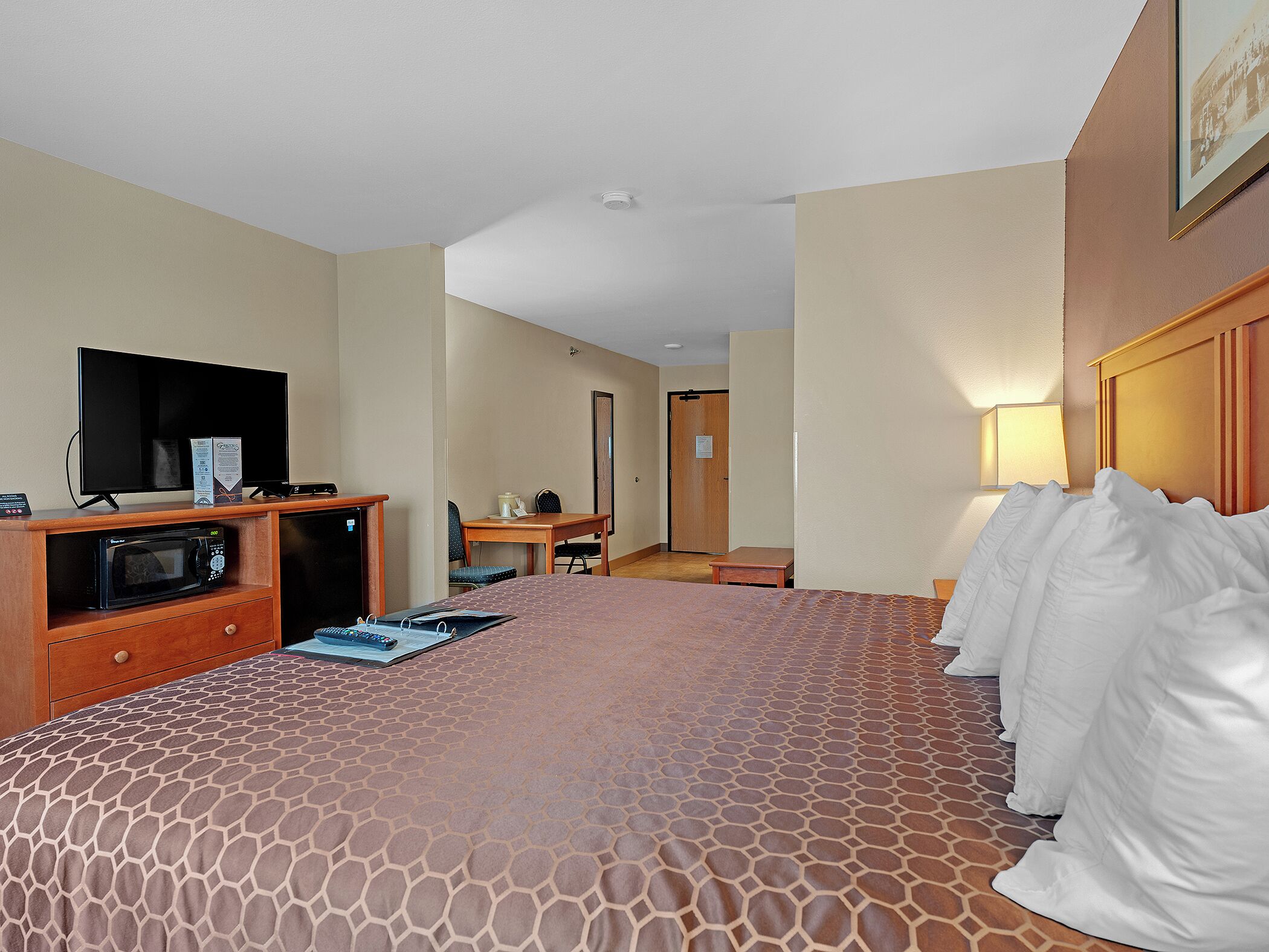 Una habitación de hotel con cama, televisión, escritorio y microondas.
