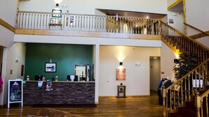 A reception area with a wooden staircase, a reception desk, and a green wall. - Bowman Lodge & Convention Center (Bowman)