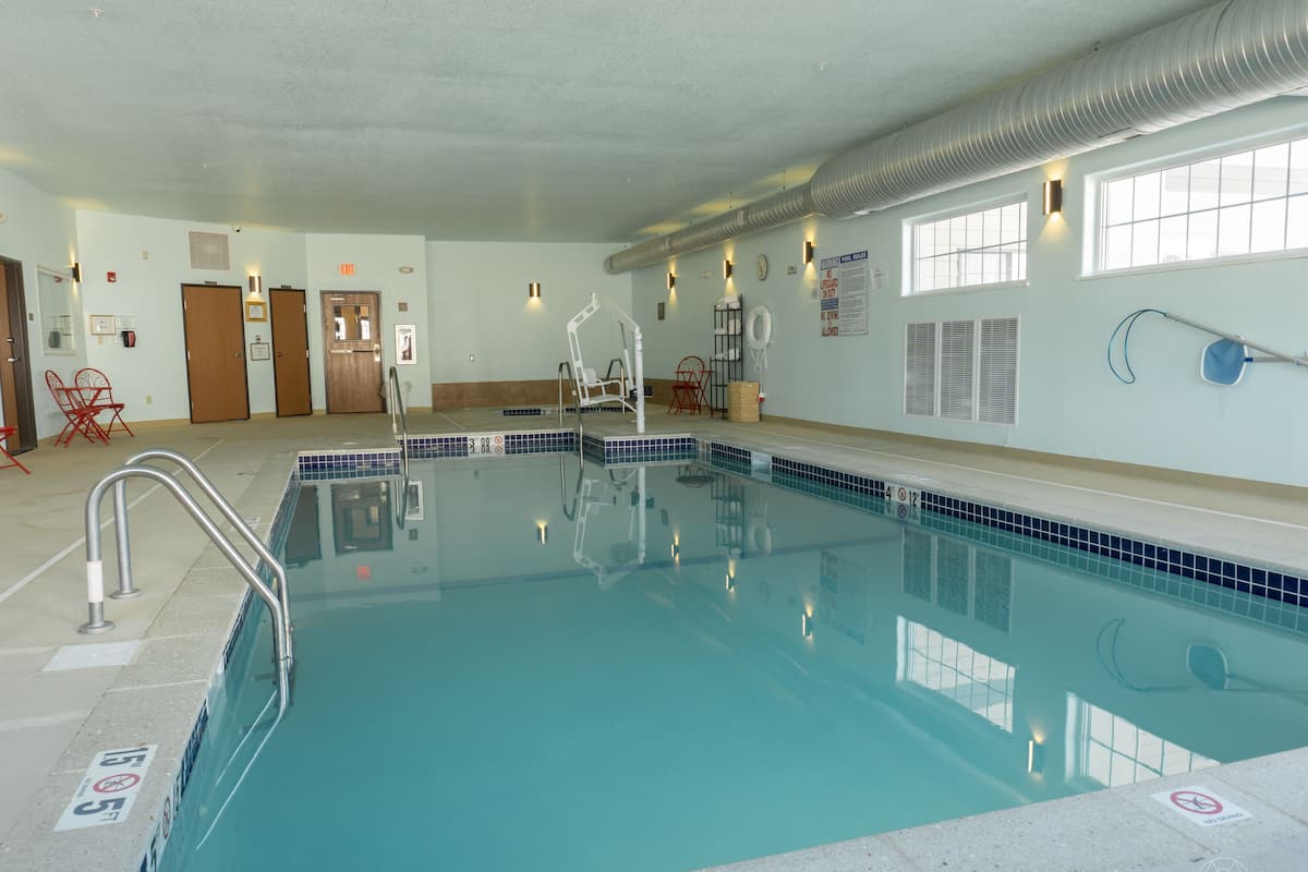 An indoor swimming pool with clear water, a lifeguard chair, and a pool ladder.