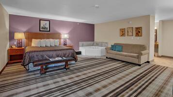 A hotel room with a bed, a bench, a sofa, a bathtub, and a wall with three framed pictures.