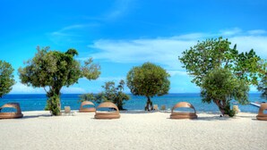 A beach with several tree-lined areas and large, round, beige structures. - BE Grand Resort Bohol (Panglao)