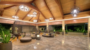 A spacious indoor area with a high ceiling, multiple seating arrangements, and potted plants. - BE Grand Resort Bohol (Panglao)