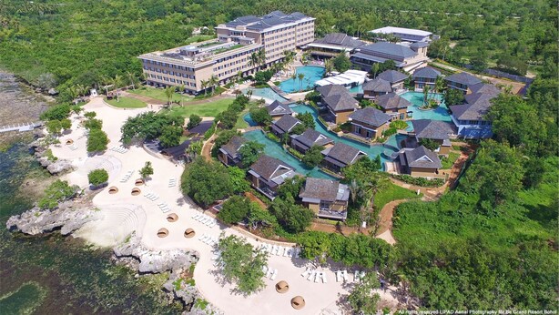 An aerial view of a resort with multiple buildings, a large pool area, and a beach with sun loungers. - BE Grand Resort Bohol (Panglao)
