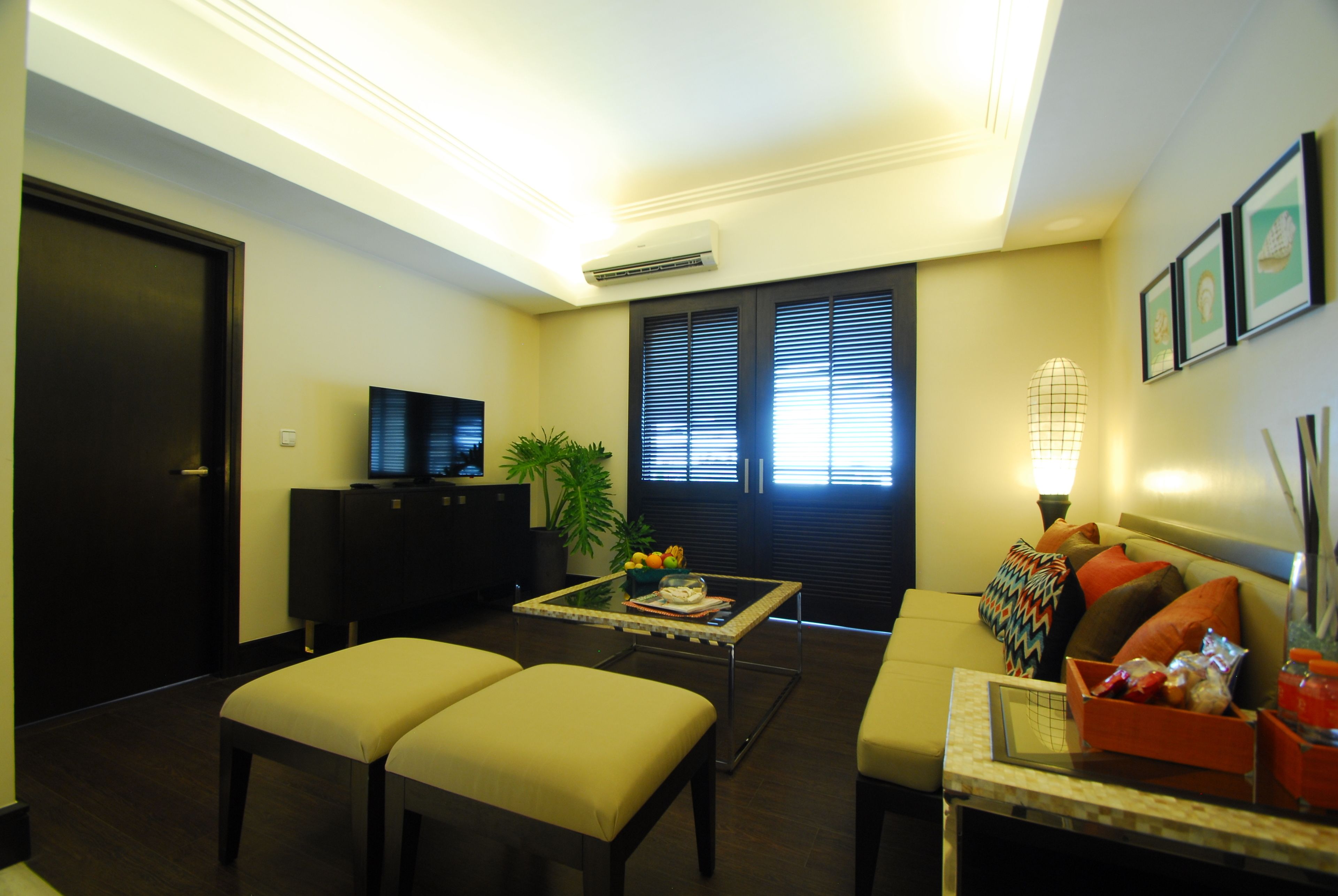 A modern living room with a sofa, two armchairs, a coffee table, and a TV.