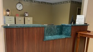En receptionsdisk med träinredning, en klocka och en skylt som anger att en deposition på 100 dollar krävs för rum som betalas kontant.