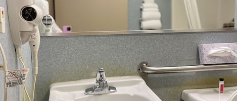Een badkamer met een wit wastafel, een haardroger, een toilet en een spiegel.