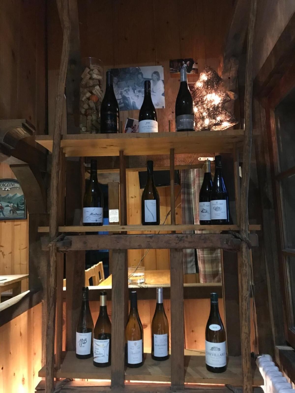 Una estantería de madera para botellas de vino, una mesa de madera y un interior rústico.