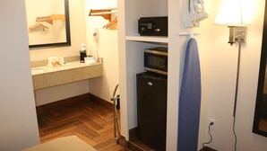 Un baño de hotel pequeño con lavamanos, espejo, microondas y un perchero para toallas.